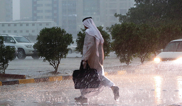 A Kuwaiti man crosses the street during a heavy rainfall in Kuwait City on November 18, 2013.  AFP PHOTO/YASSER AL-ZAYYAT||||